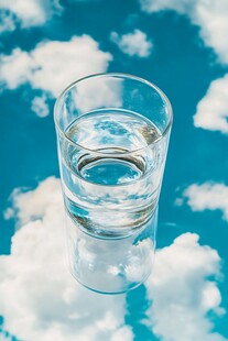 蓝天白云映在透明玻璃杯中