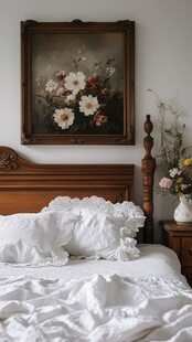 复古风格卧室 木质床头板和床尾凳 白色床单和枕头 墙上挂着花卉画 床头柜上放着花瓶
