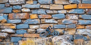 骑摩托车者穿梭于石墙前