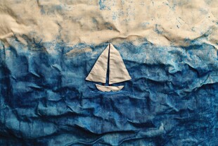 纸艺帆船在褶皱海面上航行