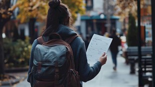 背着背包手持纸张的女孩