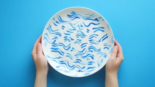 双手托举蓝白波纹陶瓷盘