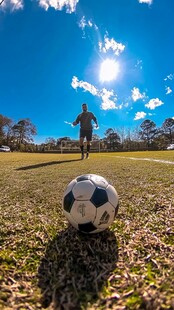 阳光下绿茵场的足球瞬间