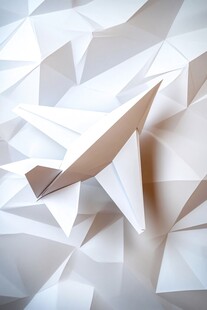 纸飞机置于几何折纸背景中