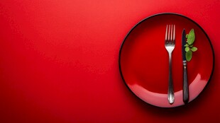 红盘上的餐具与绿叶点缀