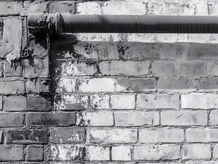 老旧砖墙旁的金属管道