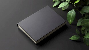 黑色书本旁的翠绿枝叶