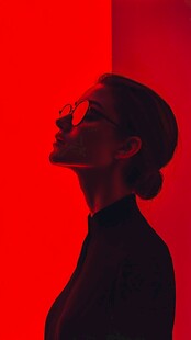 红背景下戴眼镜的女性侧影