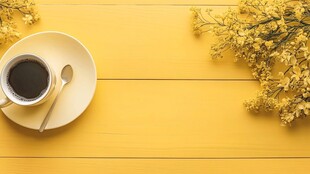 黄色木桌上的咖啡与花