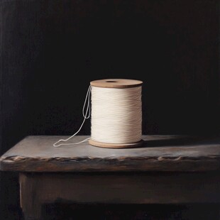 木桌上的一卷白色缝纫线