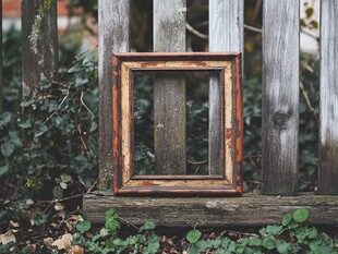 老旧相框靠于木栅栏旁