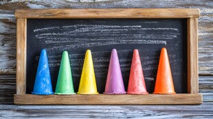 彩色圆锥摆放在木框黑板前