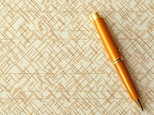 金色钢笔置于几何图案背景