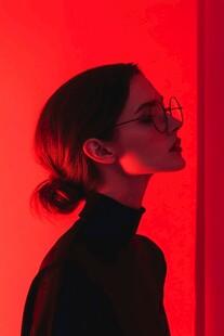 红背景下戴眼镜的女性侧影