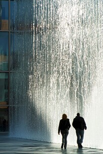 两人漫步于城市水幕墙前