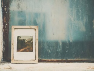 旧相框靠在斑驳墙面上
