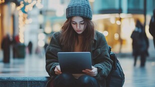 街头专注使用平板的年轻女子