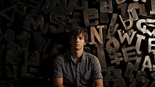 男子置身字母墙前沉思