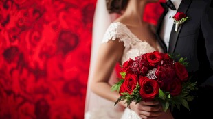 新婚夫妻手持红玫瑰捧花