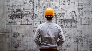 工程师凝视墙上工程图纸