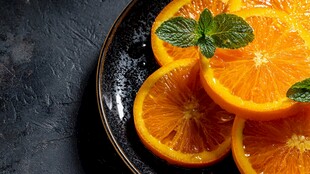 黑盘上的鲜橙与薄荷叶