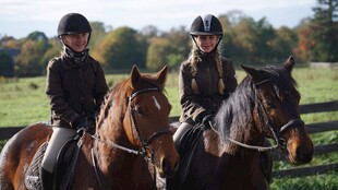 两少女骑骏马于田园间